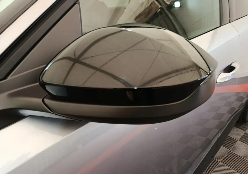 Rétroviseur droit noir brillant du Peugeot 3008 gris clair, vue rapprochée sur la portière avant.
