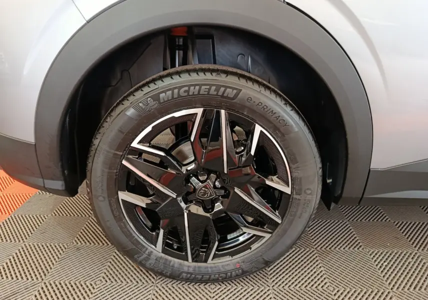 Gros plan sur la roue avant droite du Peugeot 3008 gris clair avec jante noire et détails argentés Michelin e-Primacy.