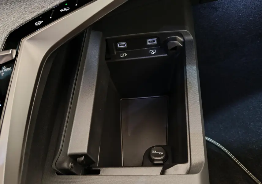 Vue rapprochée de la console centrale noire du Peugeot 3008 1.2 Hybrid 145 GT avec ports USB et prise 12V.