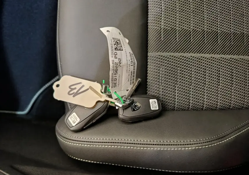 Clé de voiture Peugeot posée sur un siège avant en cuir noir avec coutures blanches, intérieur du 3008 hybride 2025.