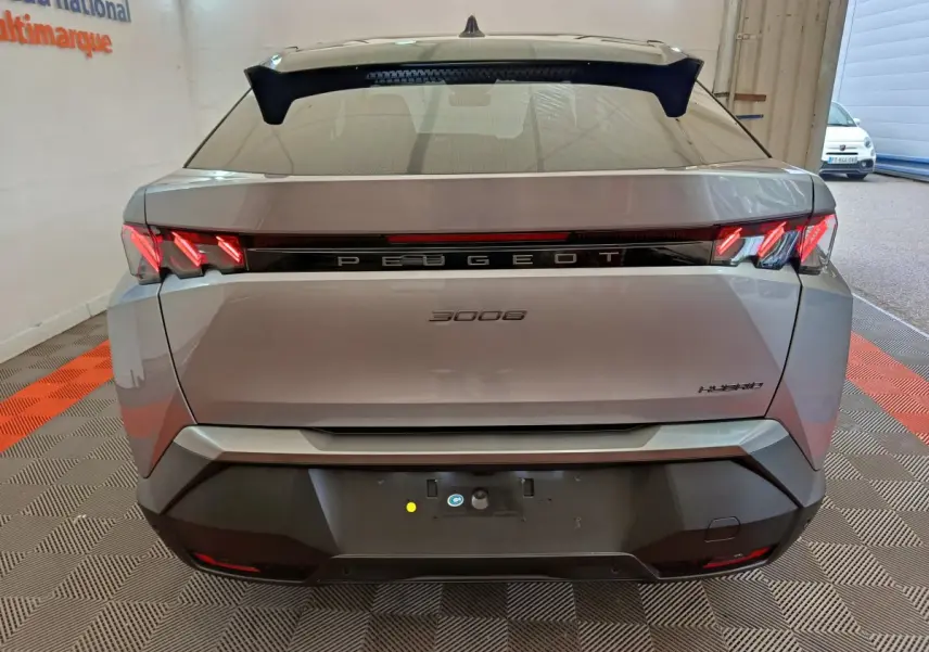 Vue arrière d'un Peugeot 3008 gris clair hybride avec feux LED distinctifs et logo central lumineux.