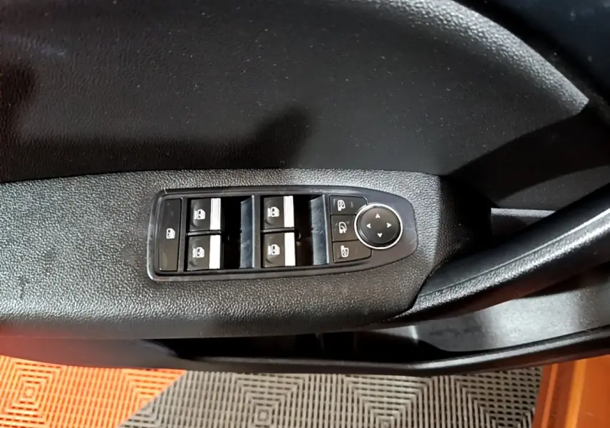 Gros plan sur les commandes de lève-vitres et rétroviseurs côté conducteur d’un Renault Captur jaune.