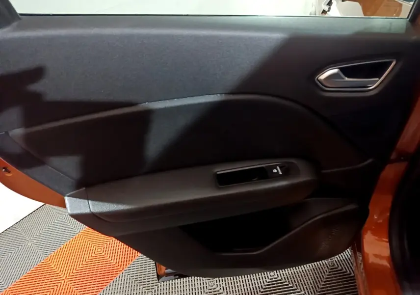 Vue intérieure du panneau de porte arrière droite du Renault Captur jaune, avec commande de vitre et poignée intégrée.