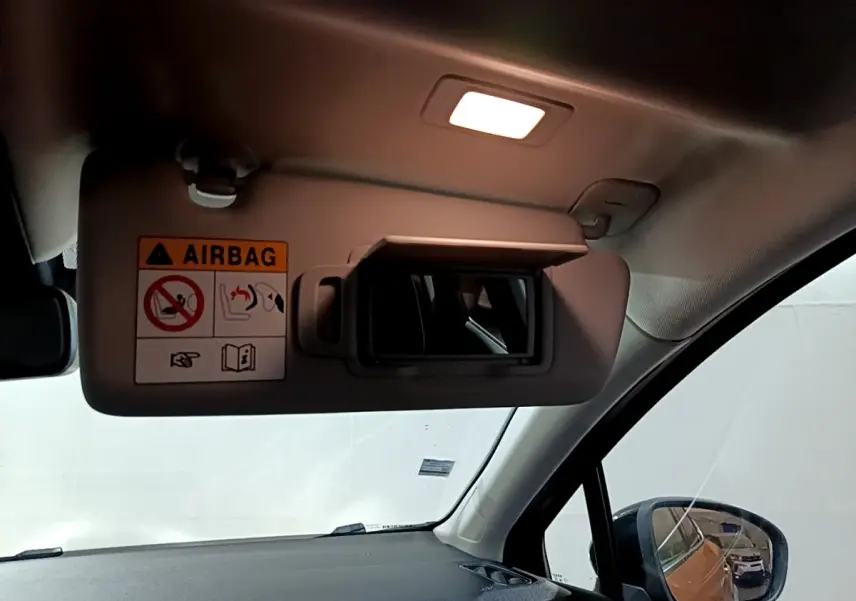 Détail du pare-soleil côté conducteur avec miroir et avertissement airbag, intérieur clair du Renault Captur jaune.