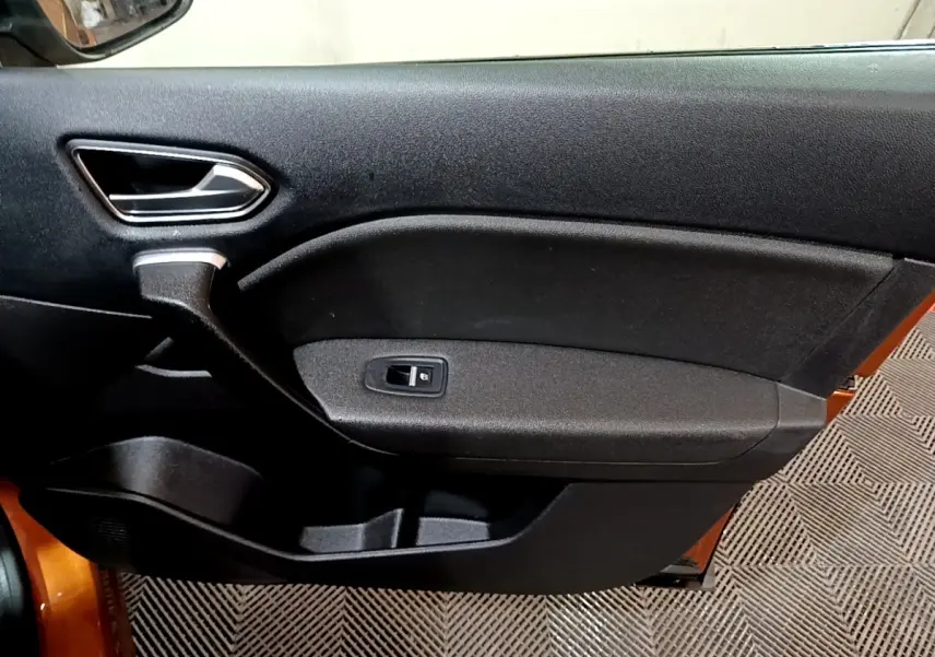 Vue intérieure du panneau de porte avant gauche noir du Renault Captur jaune 2020 avec poignée argentée et bouton de vitre électrique.
