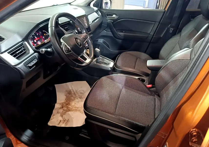 Vue intérieure côté conducteur du Renault Captur jaune 2020, montrant sièges tissu gris et tableau de bord avec écran tactile.