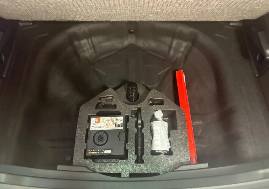 Coffre ouvert vu de dessus du SEAT Ateca 2025, montrant le rangement sous plancher avec kit de réparation et triangle de sécurité rouge.