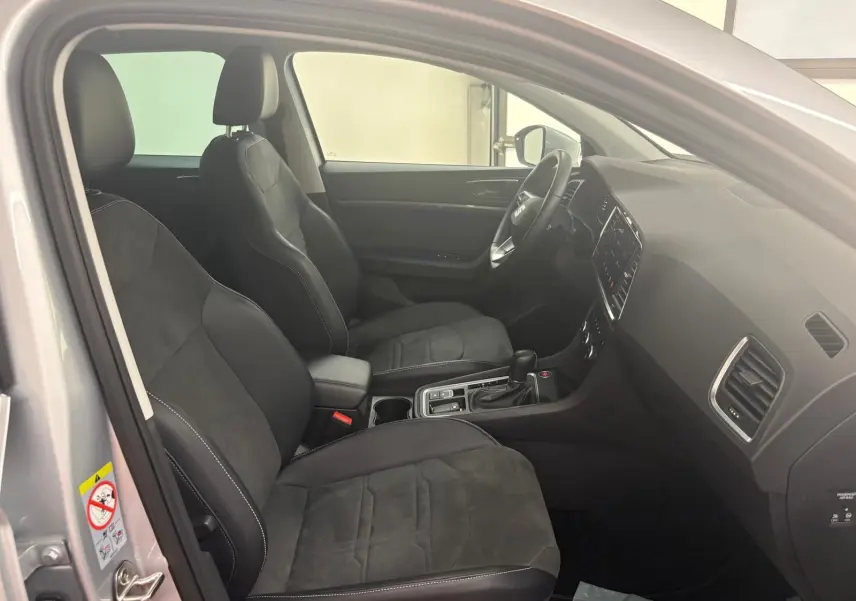 Vue intérieure côté gauche du SEAT Ateca 2025, montrant les sièges noirs et la console centrale moderne.