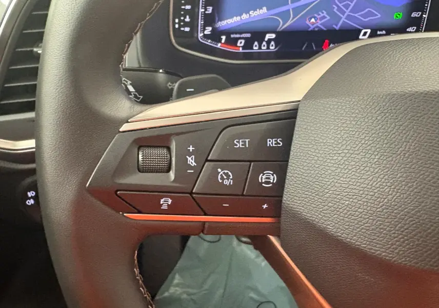 Gros plan sur les commandes au volant côté gauche du SEAT Ateca 2.0 TDI 150 DSG7 2025 avec tableau de bord numérique.