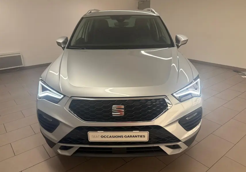 Vue avant d'un SEAT Ateca 2.0 TDI 150 DSG7 Copa argent métallisé avec phares LED allumés en intérieur.