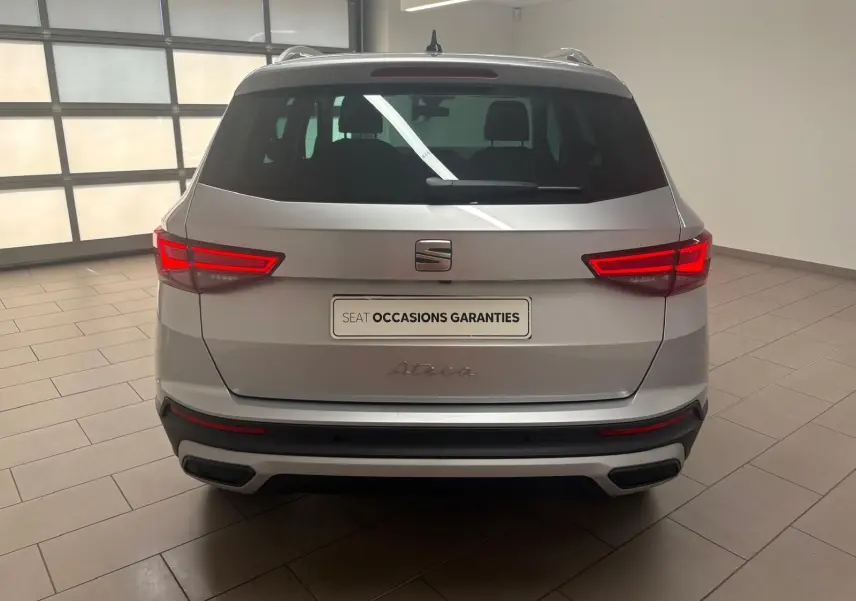 Vue arrière d'un SEAT Ateca 2025 argent métallisé avec feux LED allumés et hayon électrique en intérieur showroom.
