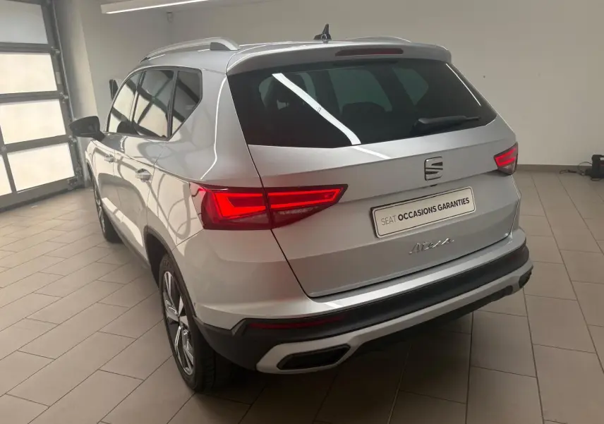 Vue 3/4 arrière droite d'un SEAT Ateca 2025 argent métallisé avec jantes alliage 18'' et hayon électrique mains-libres.