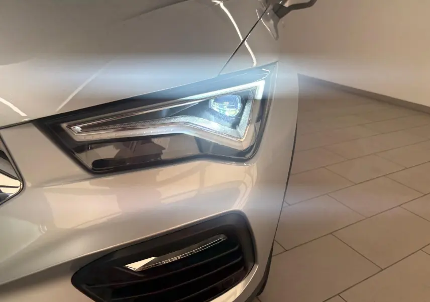 Gros plan sur le phare avant droit allumé d’un SEAT Ateca 2.0 TDI 150 DSG7 Copa en Argent Reflex métallisé.