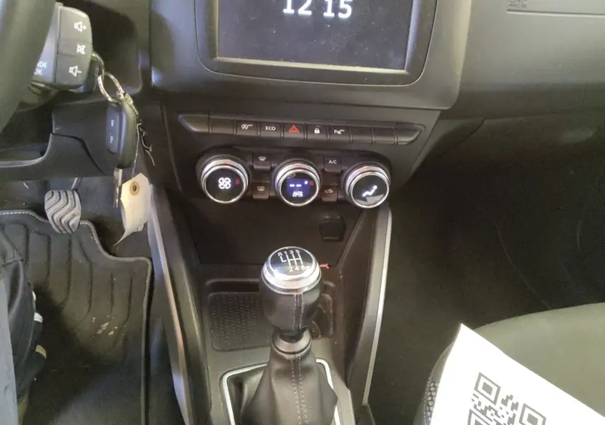 Vue intérieure centrée sur la console centrale et levier de vitesses manuel du Dacia Duster 2021, détails des commandes climatisation visibles.