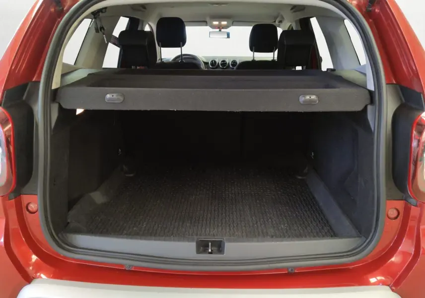 Coffre ouvert vu de l'arrière d'un Dacia Duster rouge fusion 2021, avec cache-bagages en place et intérieur noir.