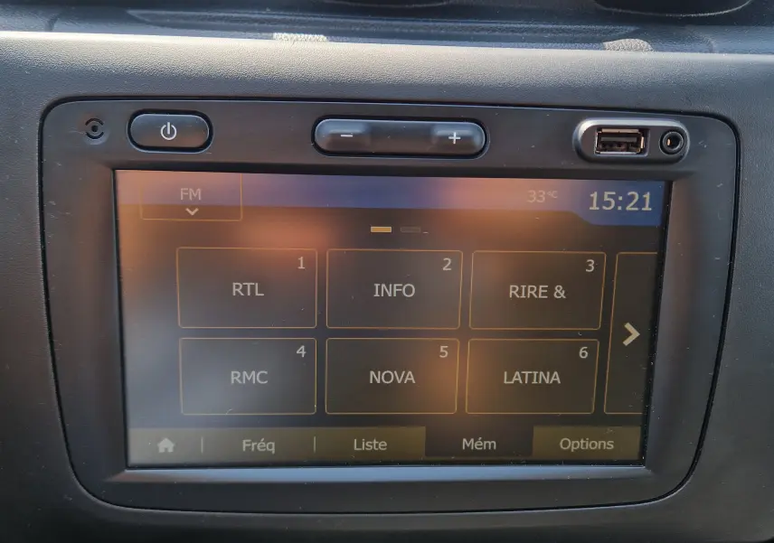Écran tactile central du Dacia Duster 2021 affichant les stations radio FM avec commandes de volume et port USB visible.