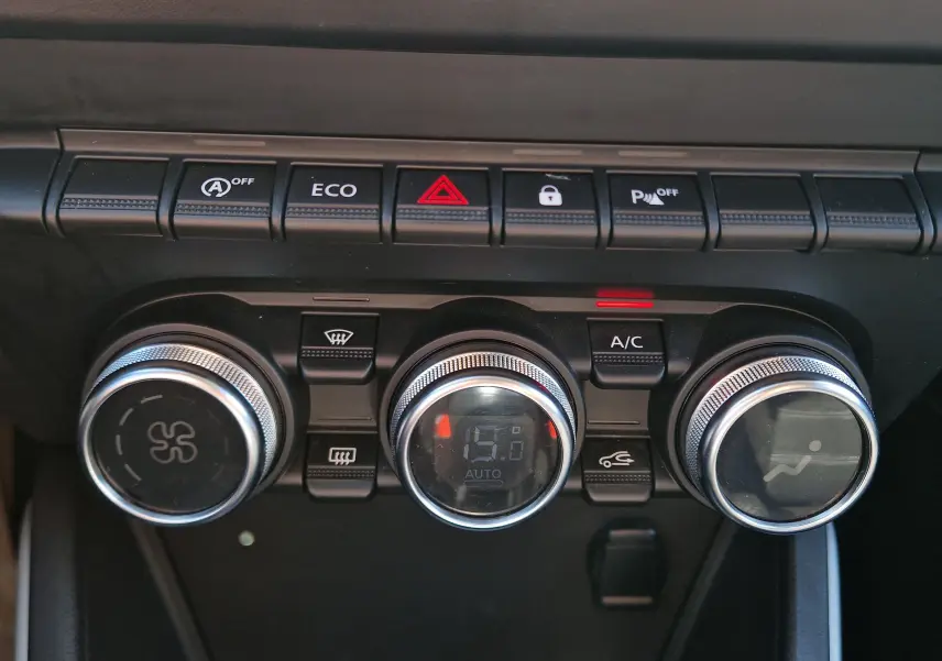 Gros plan sur la console centrale du Dacia Duster 2021, montrant les commandes de climatisation et les boutons de fonction.