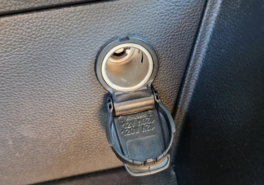 Gros plan sur la prise 12V avec couvercle ouvert dans l’habitacle du Dacia Duster rouge fusion 2021.