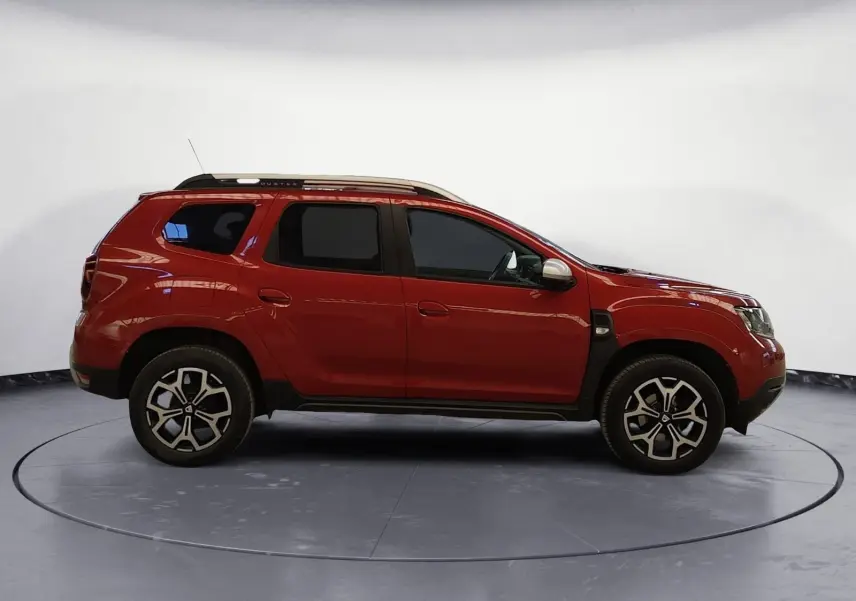 Profil droit d'un Dacia Duster 4x2 rouge fusion de 2021 avec jantes alliage et barres de toit argentées.