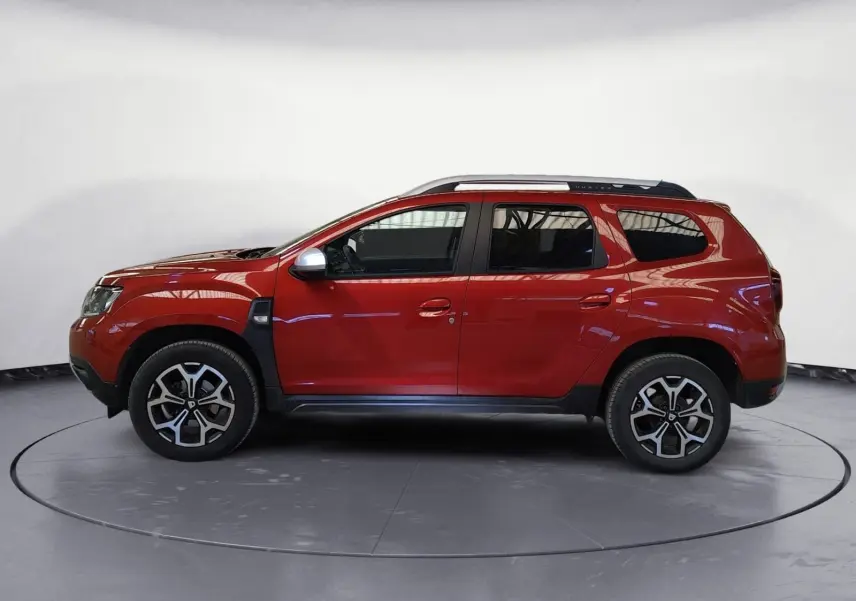 Profil droit du Dacia Duster rouge fusion 2021, version 4x2 Prestige avec jantes alliage et barres de toit.