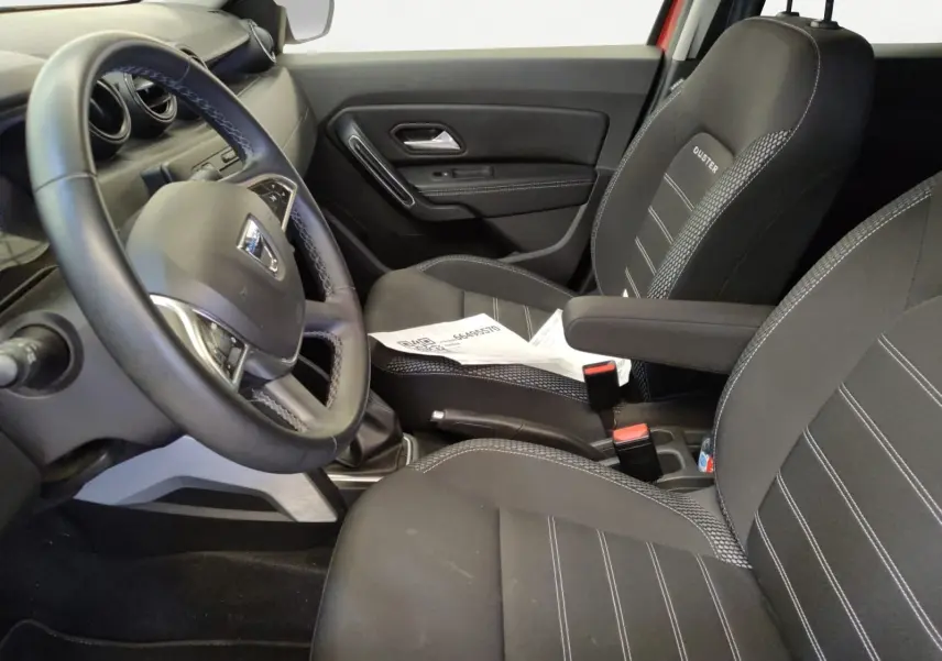 Vue intérieure côté conducteur du Dacia Duster 2021, sièges noirs avec logo Duster et volant multifonction.