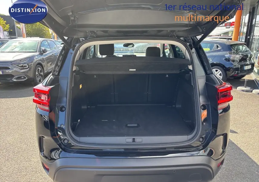 Coffre ouvert vu de l’arrière d’un Citroën C5 Aircross noir Perla Nera métal, avec banquette arrière visible.
