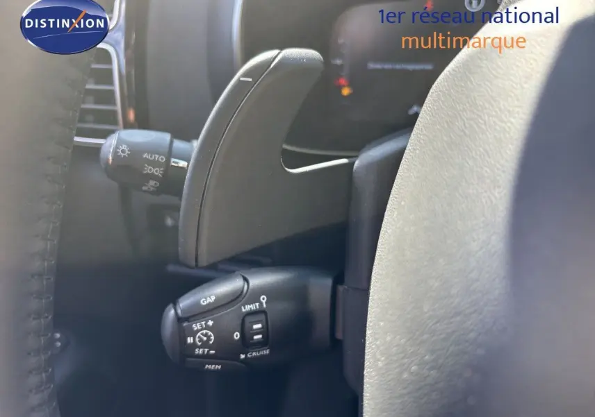 Gros plan sur la commande de régulateur de vitesse et la palette de changement de vitesse côté gauche du volant du Citroën C5 Aircross noir.