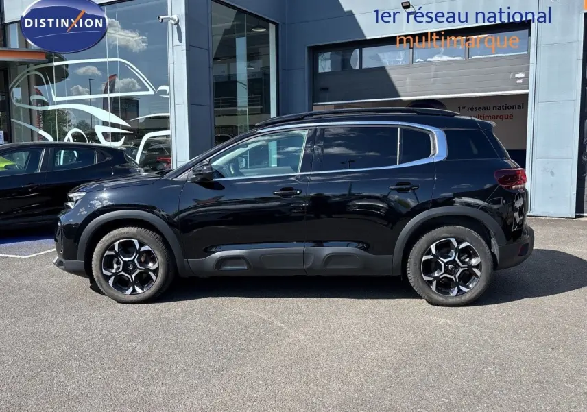 Vue latérale droite d'un Citroën C5 Aircross 2025 noir Perla Nera métallisé avec jantes bi-ton et barres de toit.