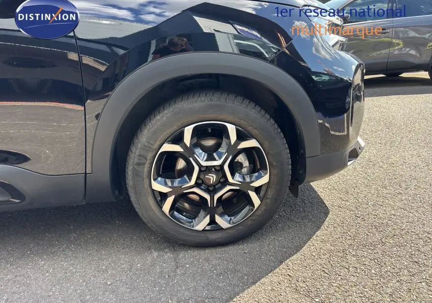 Gros plan sur la roue avant gauche du Citroën C5 Aircross noir Perla Nera métal avec jante alliage distinctive.