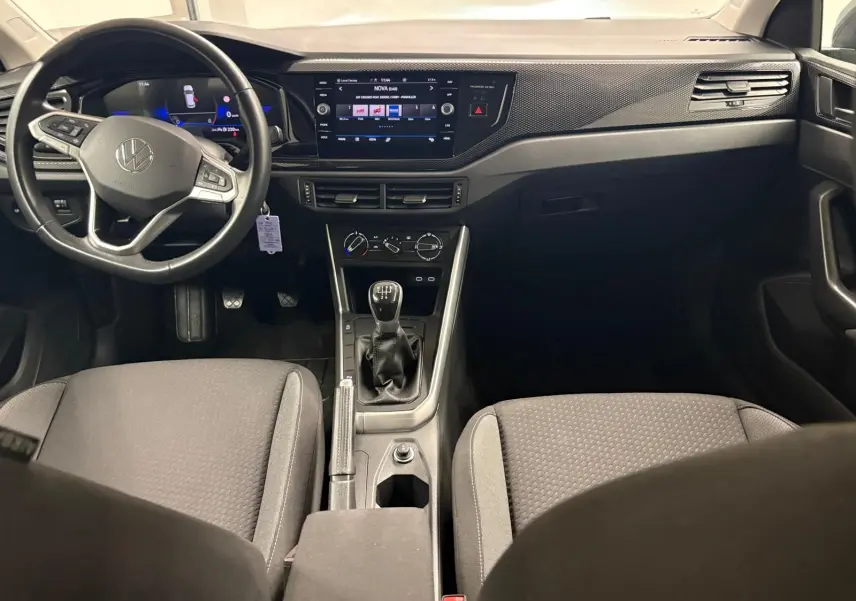 Vue intérieure avant de la Volkswagen Polo 2024 gris cendre, avec tableau de bord numérique et boîte manuelle visible.