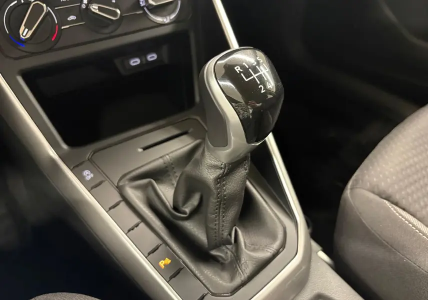 Le levier de vitesses manuel noir de la Volkswagen Polo 2024, avec commandes de climatisation en arrière-plan.