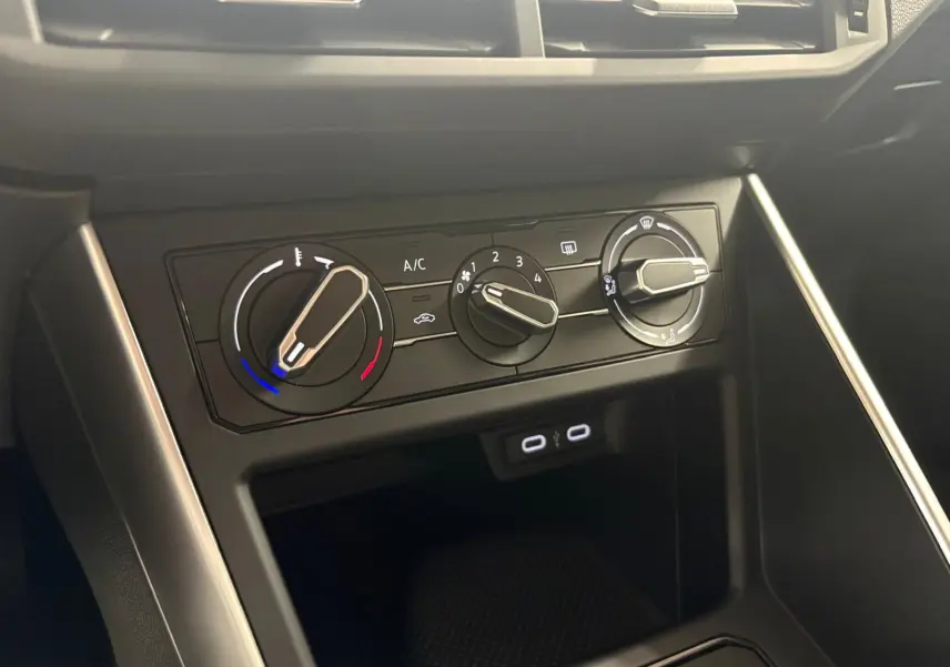 Gros plan sur les commandes de climatisation de la Volkswagen Polo gris cendre 2024, avec boutons rotatifs et ports USB.