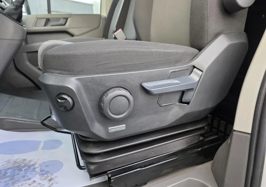 Gros plan sur le siège conducteur gris foncé avec réglages manuels dans un Volkswagen Crafter Fourgon blanc 2023.
