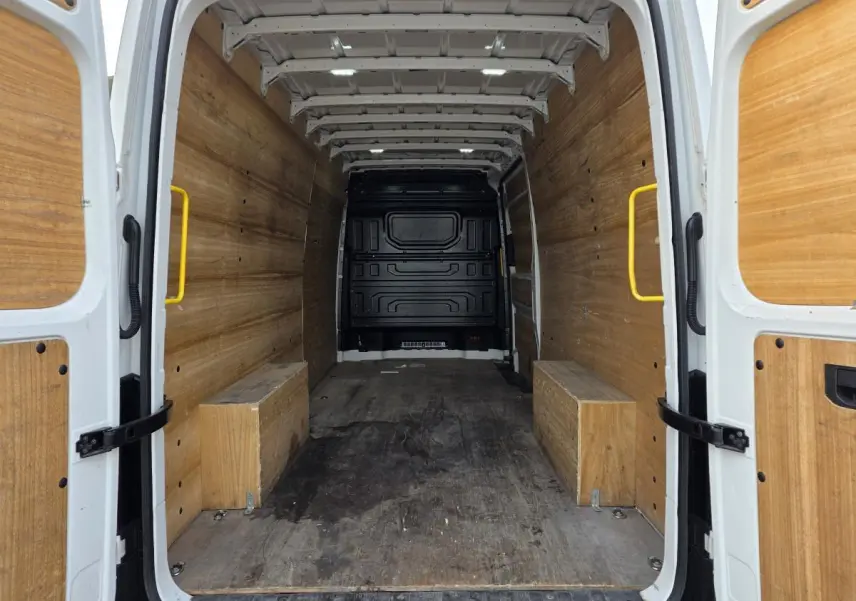 Vue arrière intérieure du Volkswagen Crafter blanc, montrant l'espace de chargement avec plancher et parois en bois.
