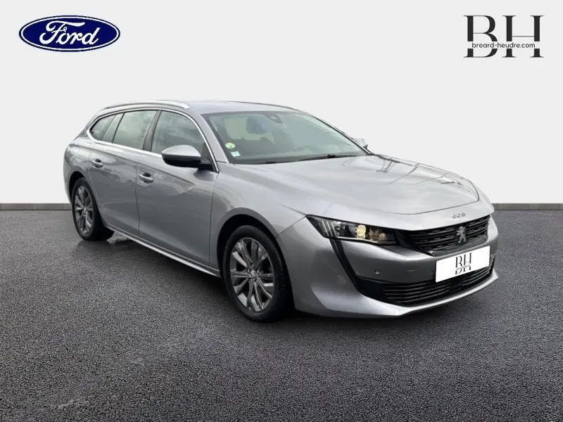 Peugeot 508 SW gris Platinium vue 3/4 avant droit, mettant en valeur sa calandre noire et ses jantes alu.