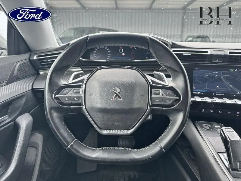 Vue intérieure centrée sur le volant cuir noir du Peugeot 508 SW 2020 avec tableau de bord numérique et écran tactile.
