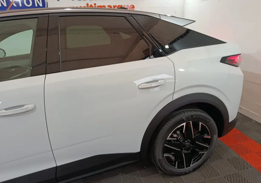 Vue côté droit arrière du Peugeot 3008 blanc avec jante noire et vitres teintées dans un showroom.