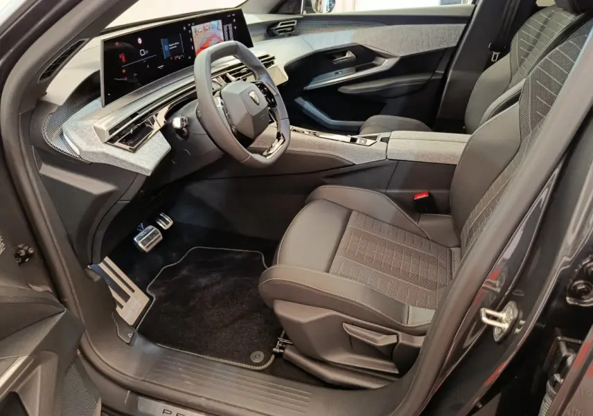 Intérieur avant droit du Peugeot 3008 blanc 2025, avec tableau de bord numérique et sièges en tissu gris.