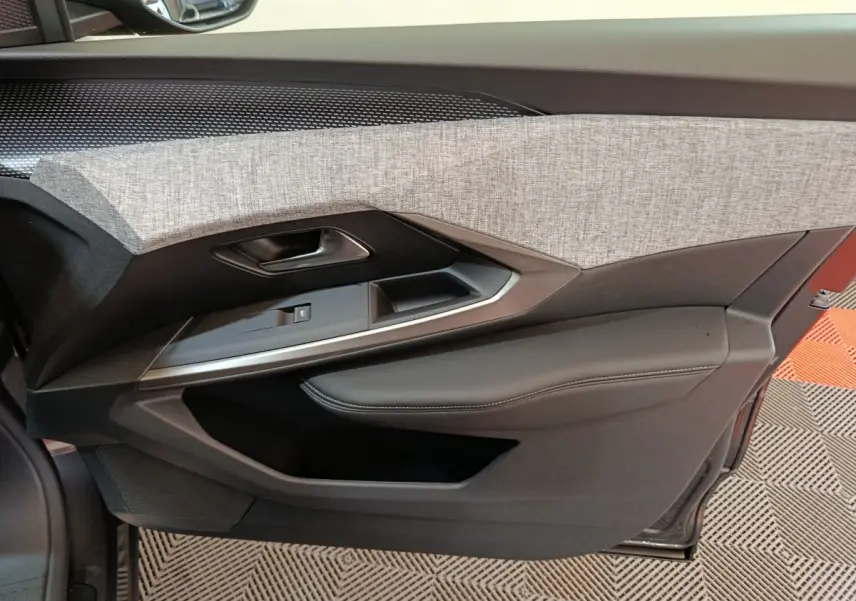 Gros plan sur la porte côté gauche du Peugeot 3008 blanc, avec garniture tissu gris et accoudoir noir cuir.
