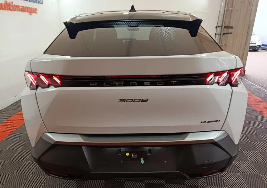 Vue arrière d'un Peugeot 3008 blanc hybride 2025 avec feux LED distinctifs allumés dans un garage.