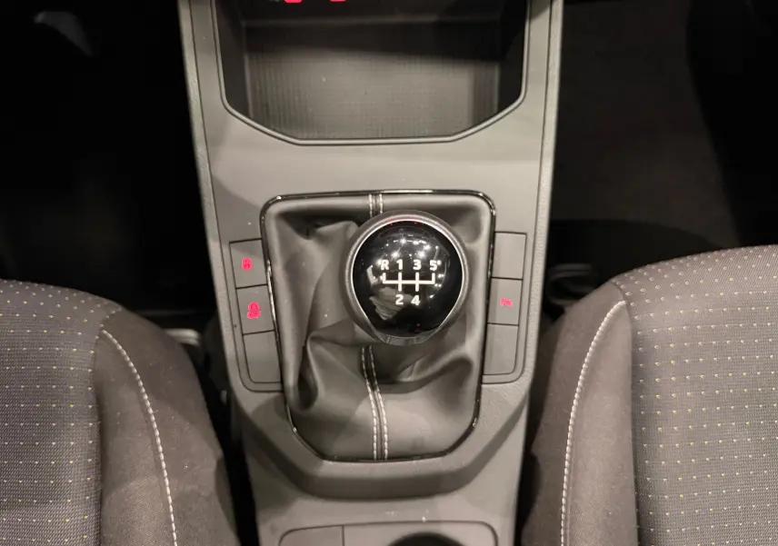 Le levier de vitesses manuel noir de la SEAT Ibiza 1.0 TSI 95CH Copa 2025, entouré des sièges en tissu gris à motifs.