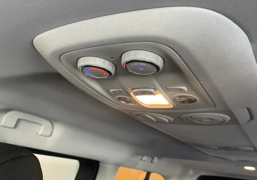 Plafonnier intérieur avec commandes de climatisation arrière et éclairage allumé dans un Peugeot Traveller noir.