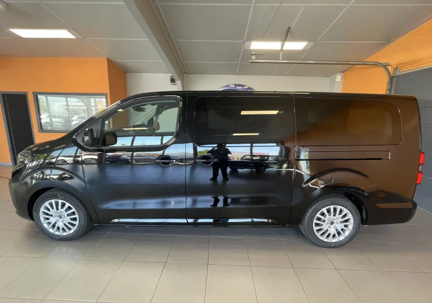 Peugeot Traveller noir vu de profil côté gauche, avec portes coulissantes et jantes alliage visibles en intérieur.