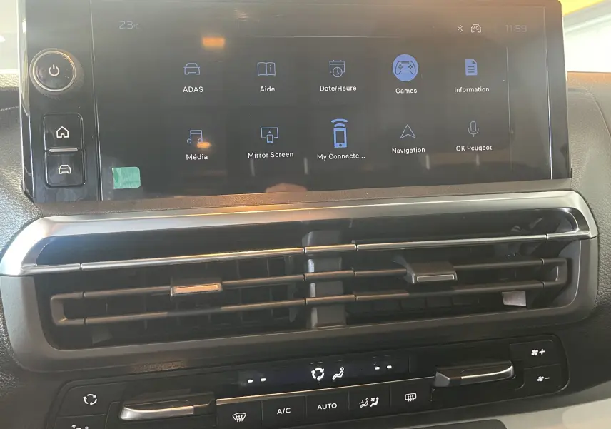 Vue rapprochée de l’écran tactile central et des commandes de climatisation du Peugeot Traveller noir 2026.