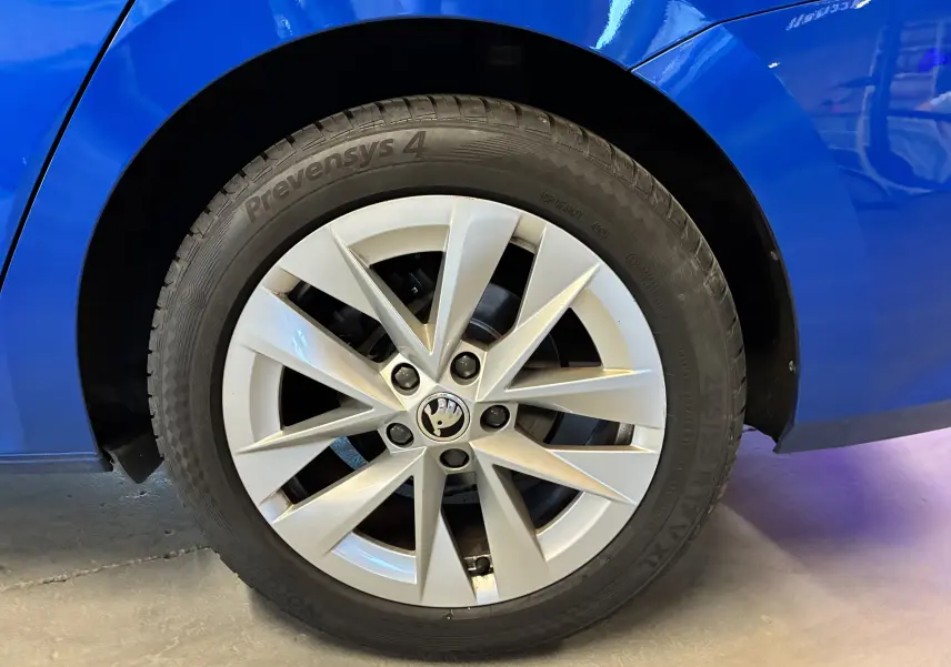 Gros plan sur la roue avant droite d’une Skoda Octavia Combi 2024 bleu, avec jante alliage et logo Škoda au centre.