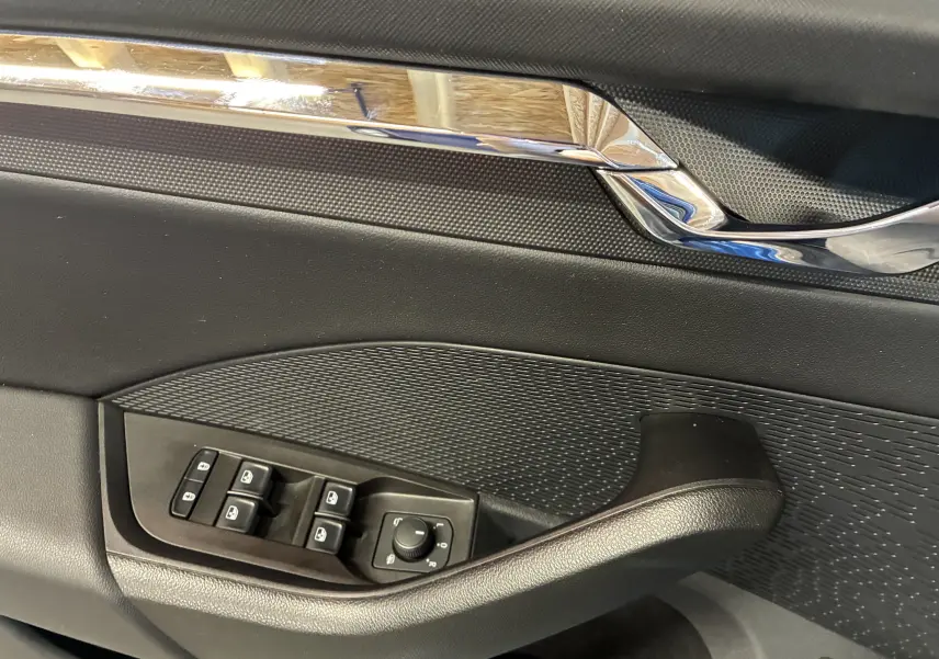 Détail de la porte côté conducteur de la Skoda Octavia Combi 2024, avec commandes de vitres et rétroviseurs, finition noire.