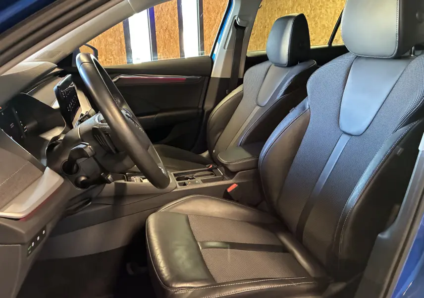 Vue intérieure côté conducteur de la Skoda Octavia Combi 2024, sièges en cuir noir et tableau de bord moderne.