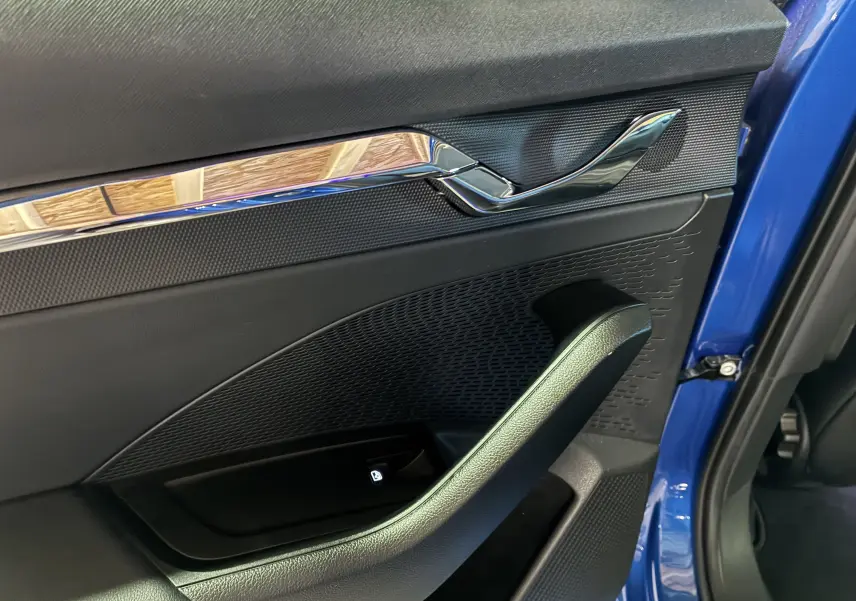 Détail de la porte avant gauche d’une Skoda Octavia Combi 2024 bleu, avec poignée intérieure chromée et bouton de verrouillage.