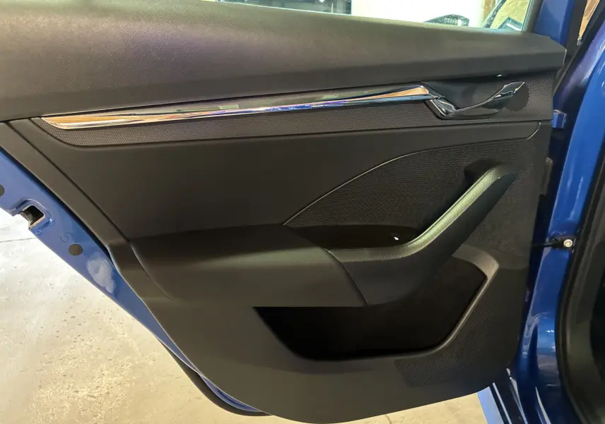 Vue rapprochée de la porte arrière droite bleu vif d'une Skoda Octavia Combi 2024, avec garniture intérieure noire et insert chromé.