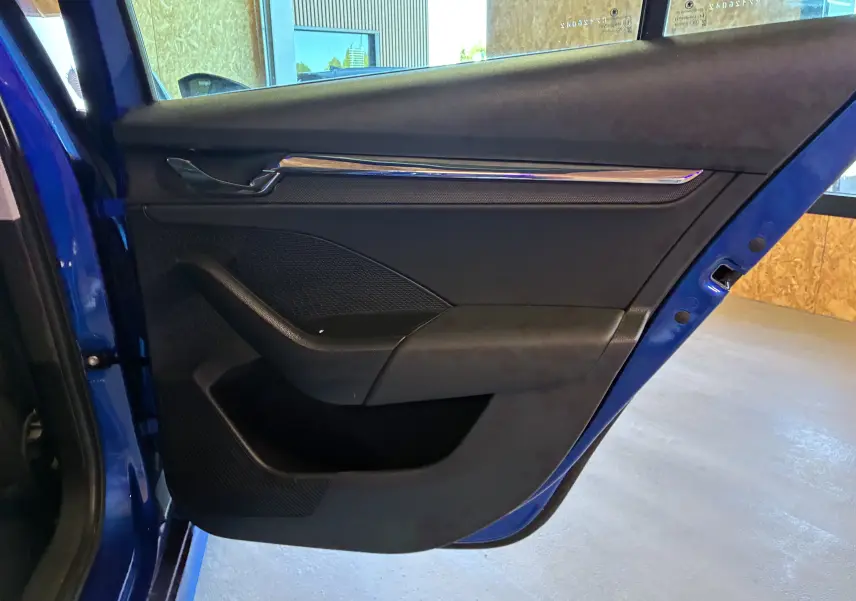 Vue rapprochée de la porte arrière gauche bleu foncé du Skoda Octavia Combi 2024 avec garniture intérieure noire et insert chromé.